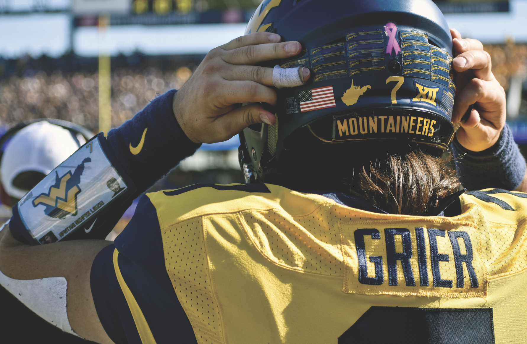 Will Grier adjusting his helmet strap before his play.